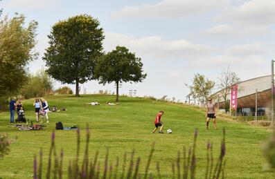 People lie or play in the sun at Queen Elizabeth Olympic Park