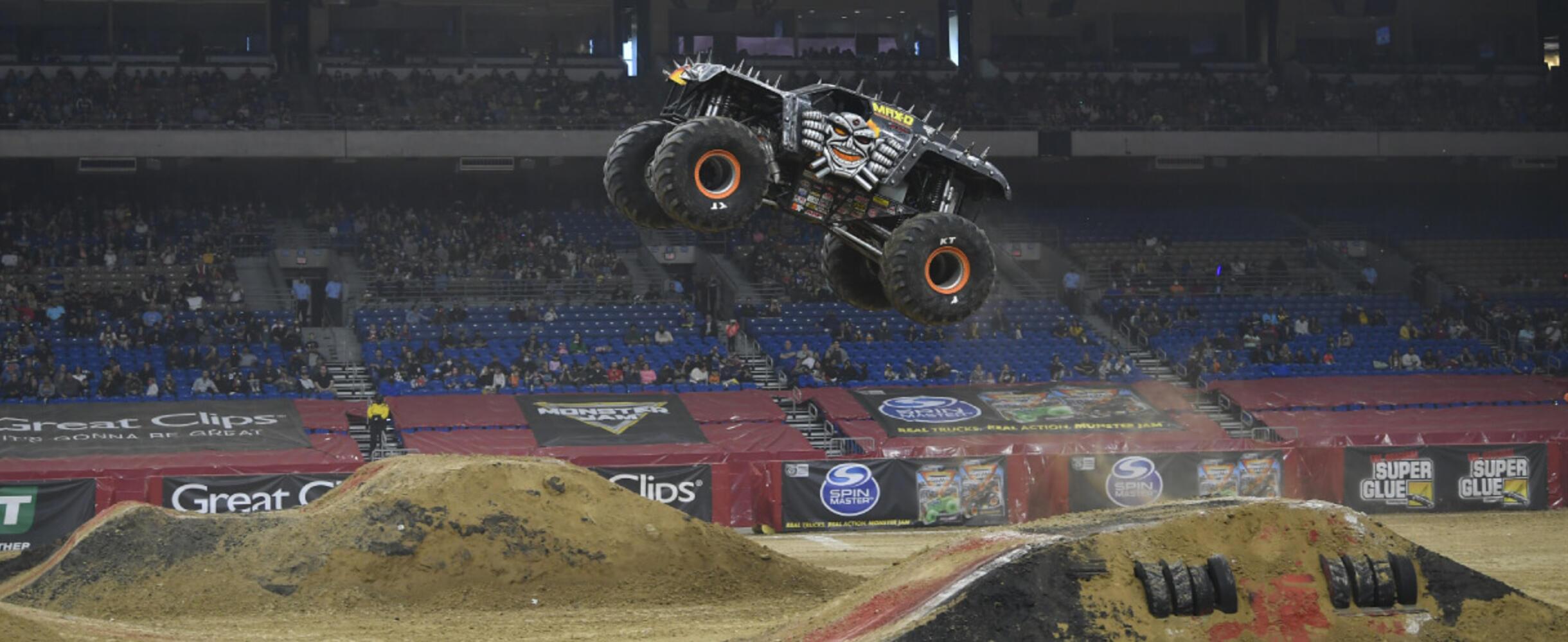A Monster Jam truck flies high in the air over a jump