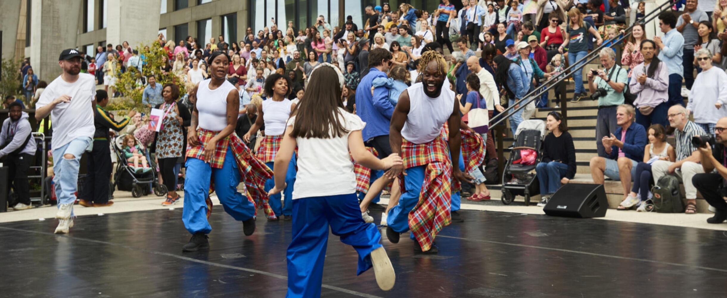 A group of dancers on stage with the crowd behind