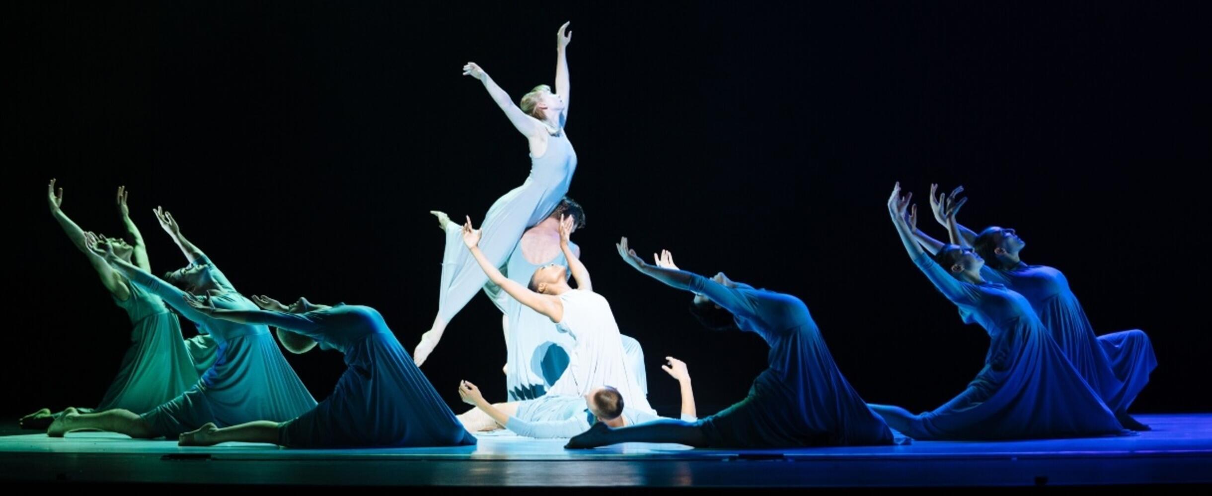 A dance performance in blue and green light