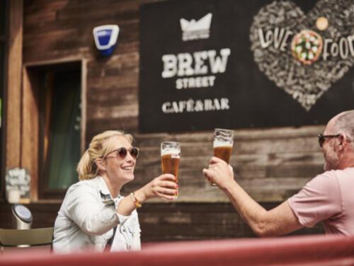 Two people cheers their drinks outside Timber Lodge Cafe