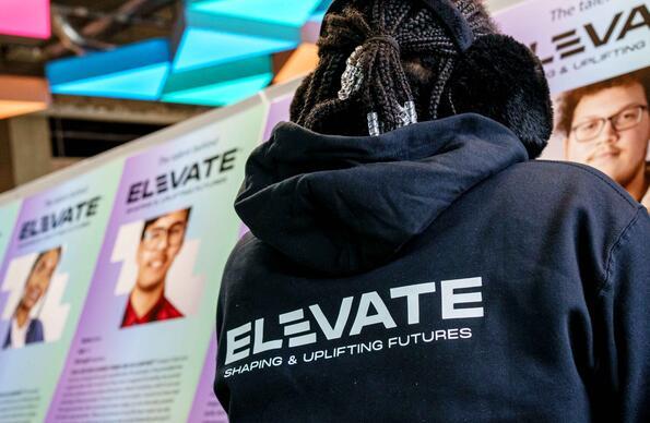 Person looking at headshots wearing a hoodie that reads Elevate Person looking at headshots wearing a hoodie that reads Elevate