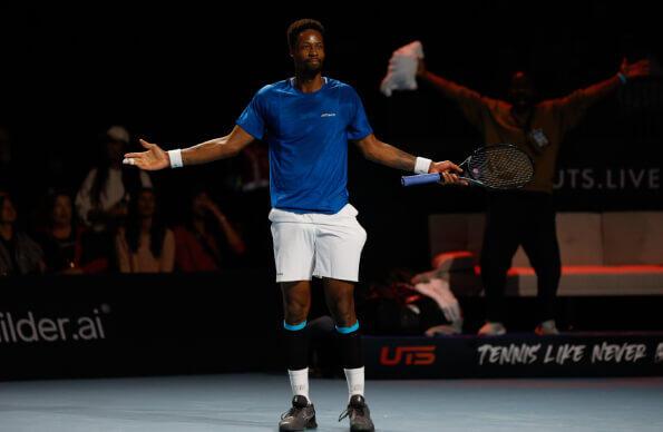 A tennis player stands with arms spread out