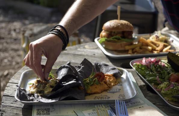 A hand picks up some food from a plate at Barge East