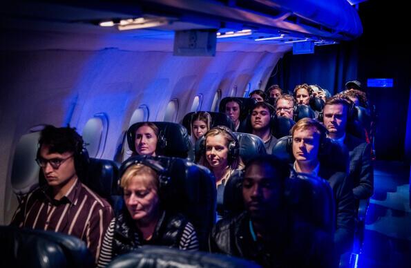 A group of people at FLIGHT, an immersive performance set on a plane A group of people at FLIGHT, an immersive performance set on a plane