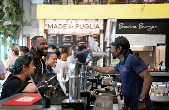 Three people are served drinks at the bar at Hackney Bridge