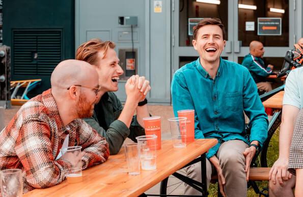 three people sit on a bench, laughing