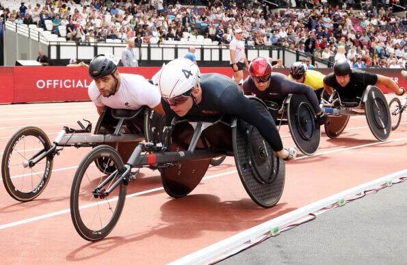 A group of para-athletes in wheelchairs racing on London Stadium track