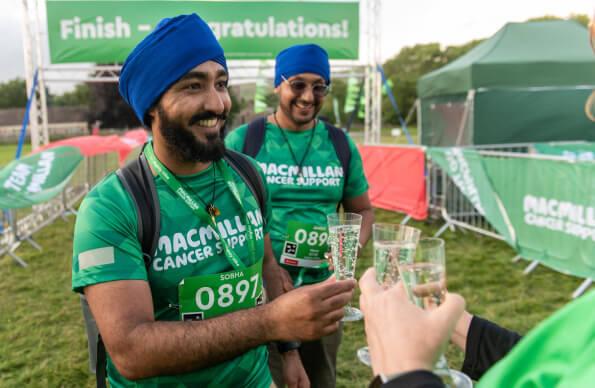 Two people celebrate finishing the Macmillan Mighty Hike with a glass of sparkling wine