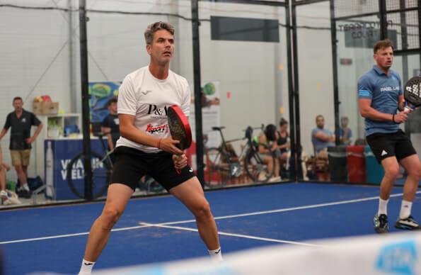 A Padel player readies themselves to return a serve