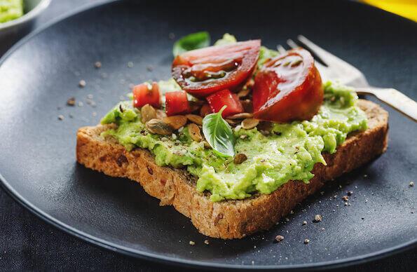 An avocado toast on a black plate