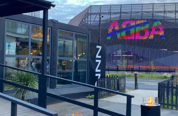 The entrance of snoozebox hotel with ABBA Voyage behind