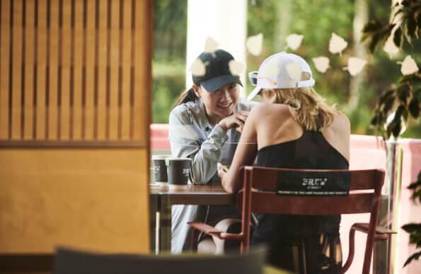 Two people sit outside Timber Lodge, drinking coffee