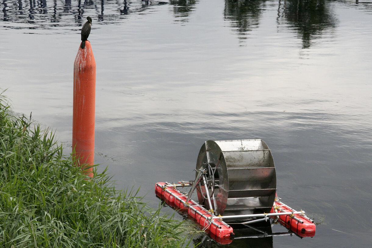 Water wheel floating by bank