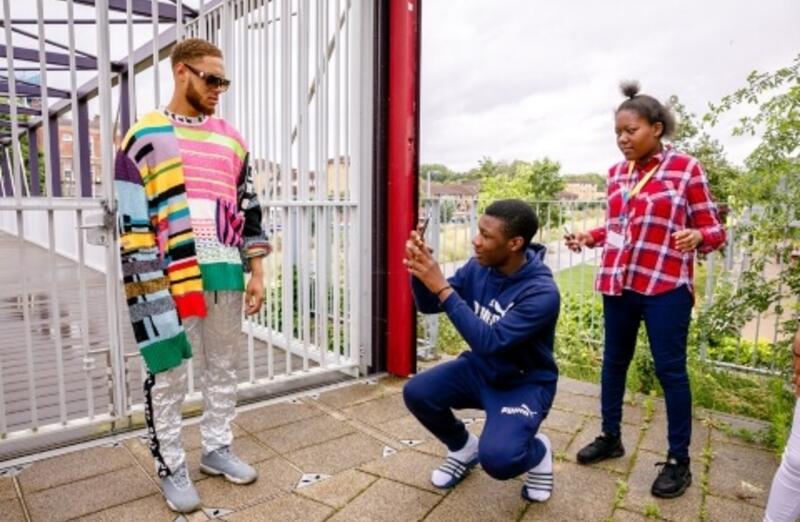 A male model in a colourful sweater poses for an outdoor photoshoot